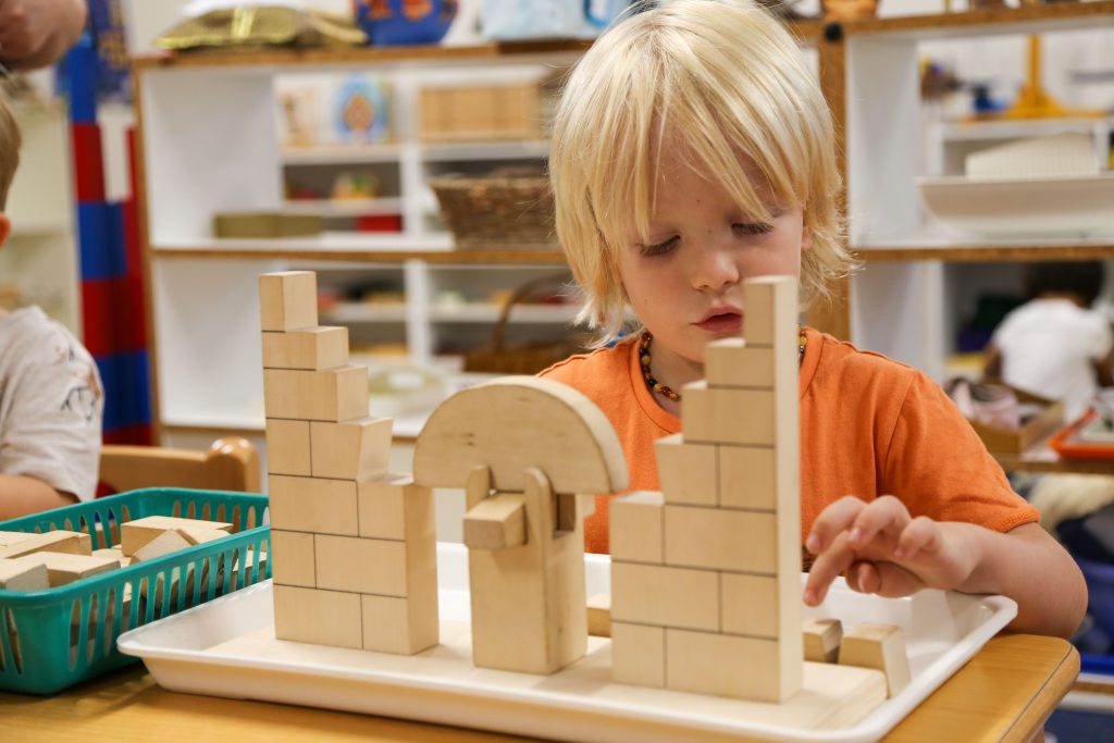 A student is building a structure with wooden blocks